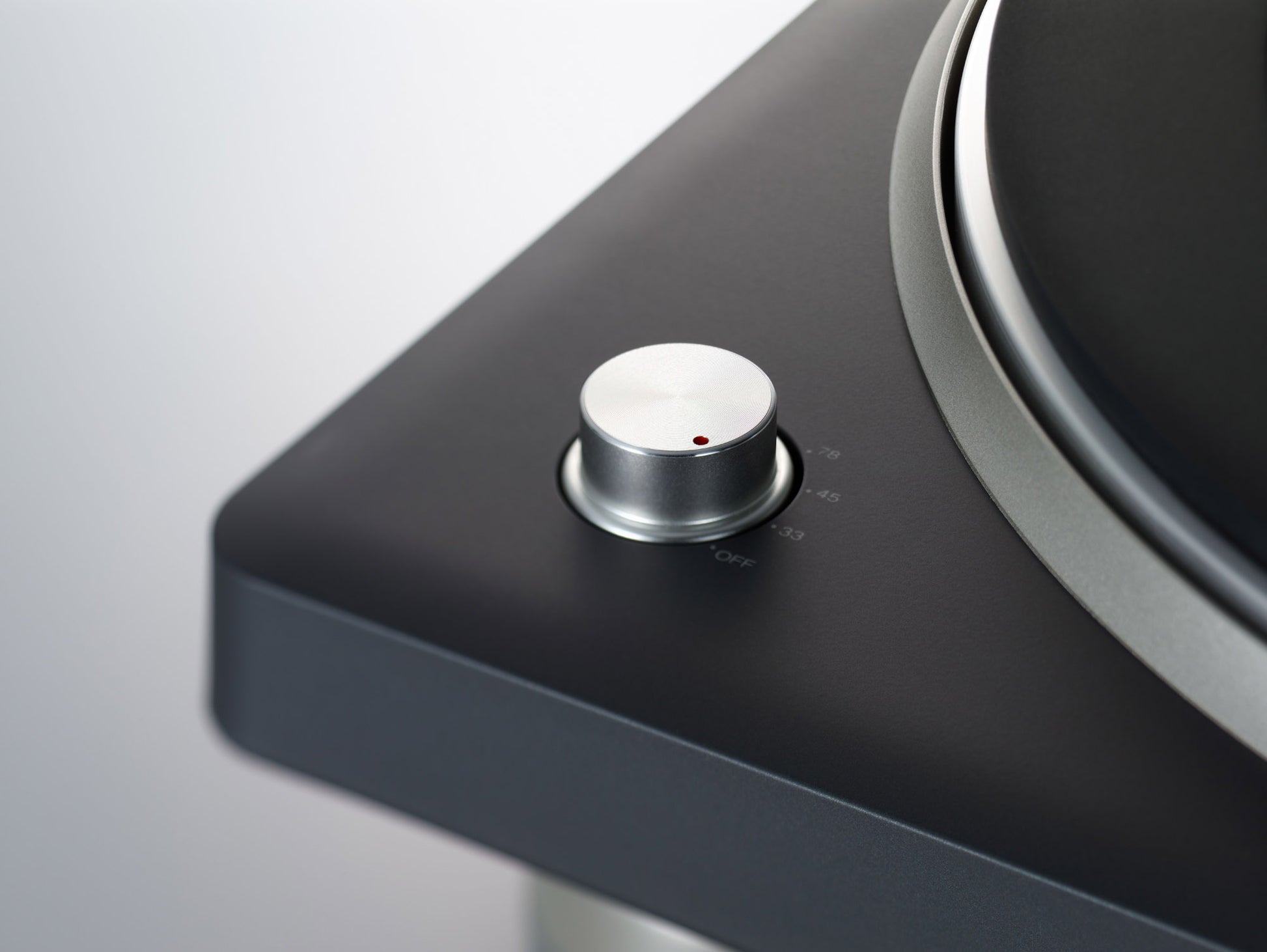 Close-up of a turntable with a control knob on a gray background
