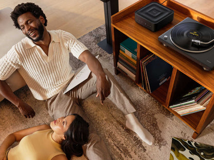 Man and woman sitting on a rug in a living room with a record player and records.