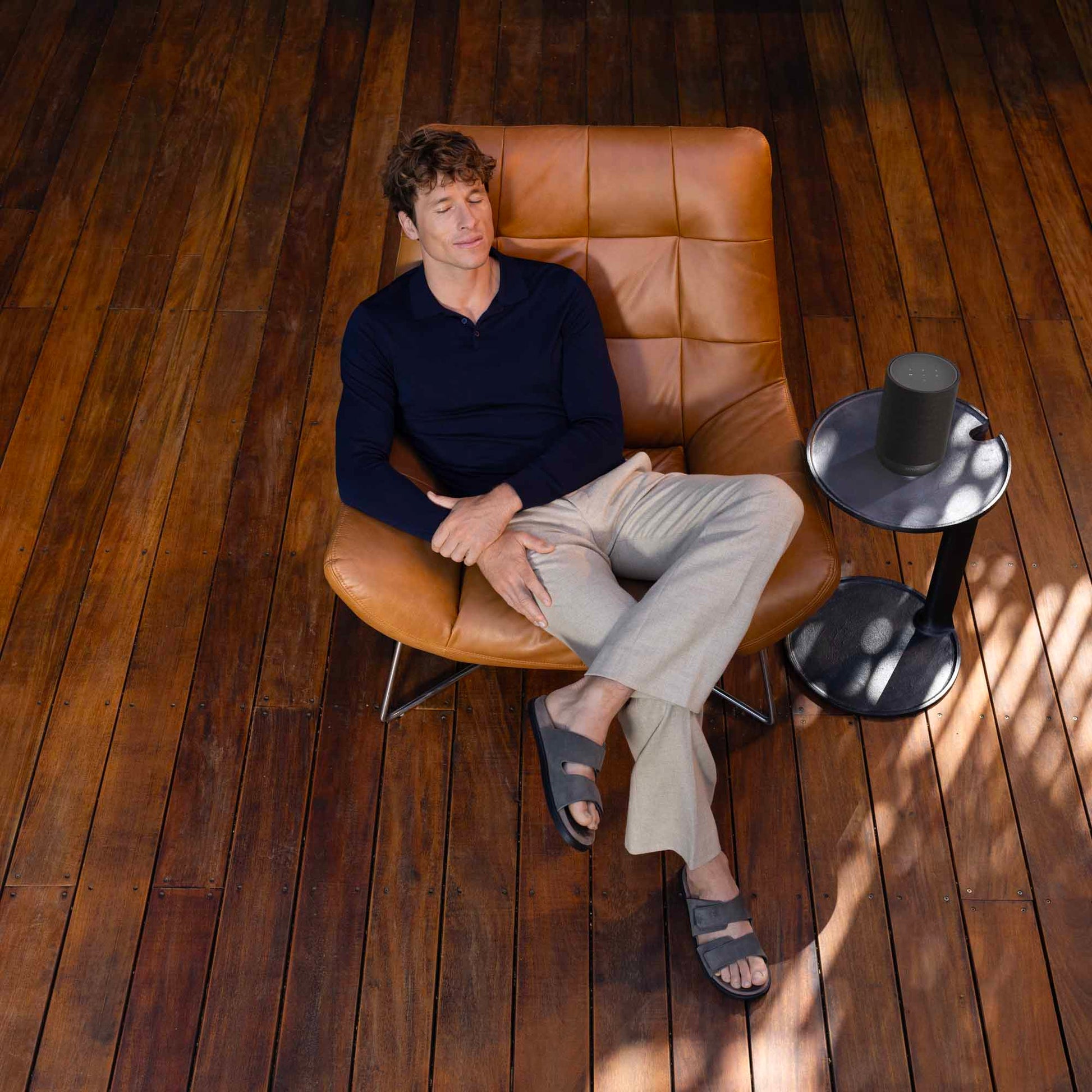 Man sitting on a brown leather chair in a room with wooden flooring