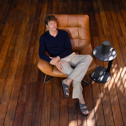 Man sitting on a brown leather chair in a room with wooden flooring