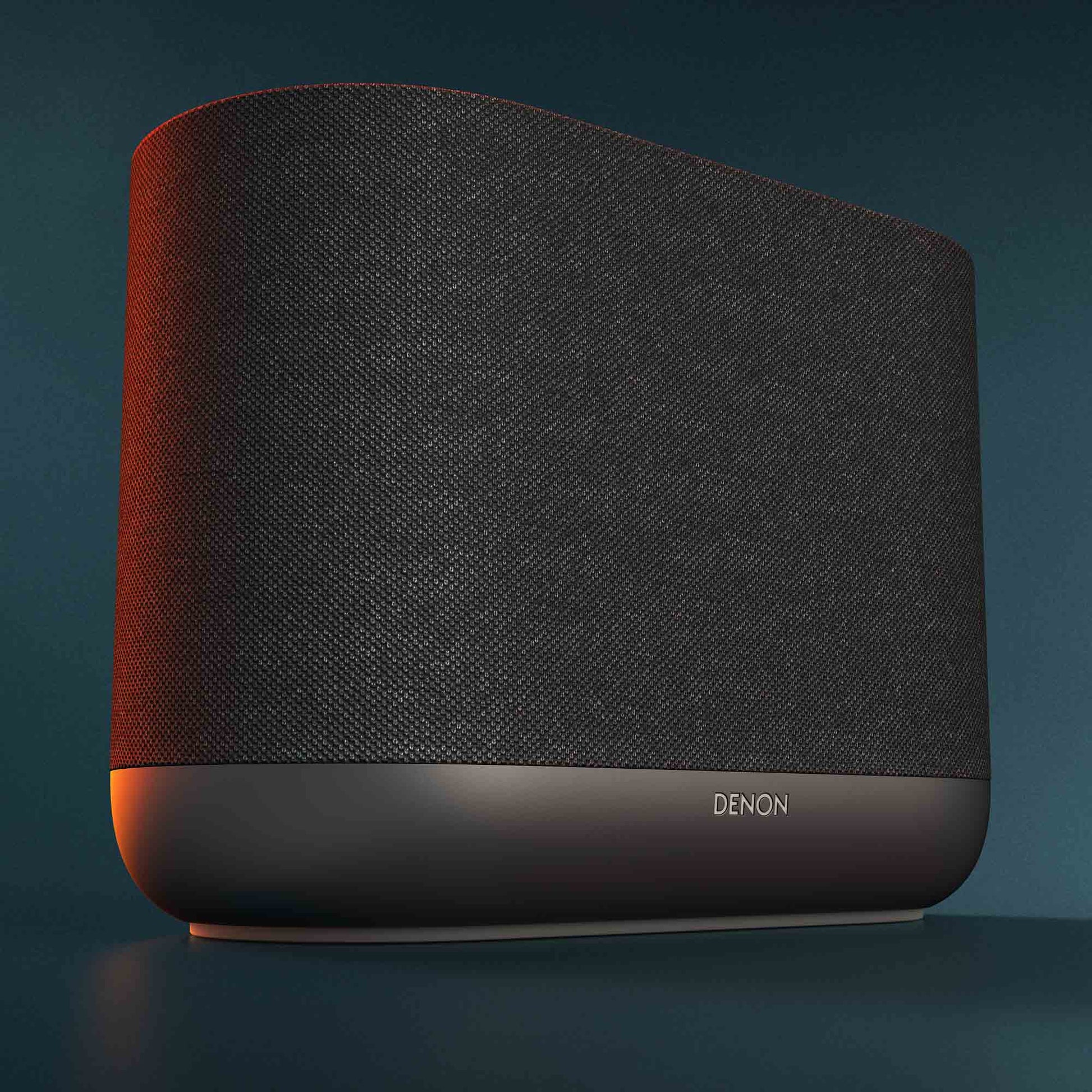 Close up of black Denon Home 400 wireless smart speaker on dark green background