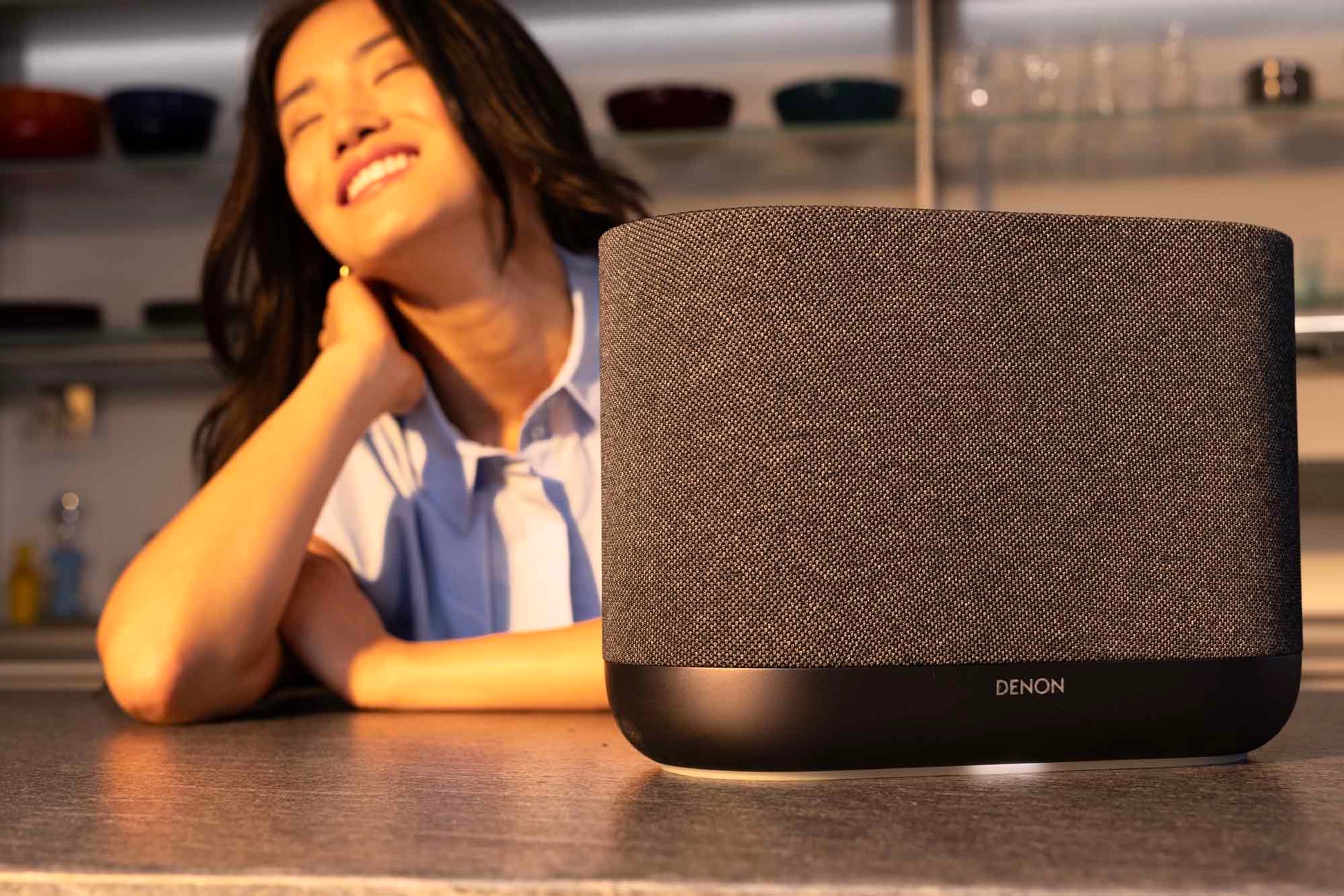 Lady listening with her eyes closed to the black Denon Home 400 wireless smart speaker