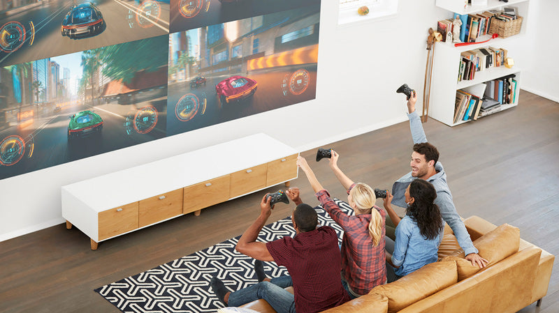 Group of people playing video games together in a living room with projection on wall