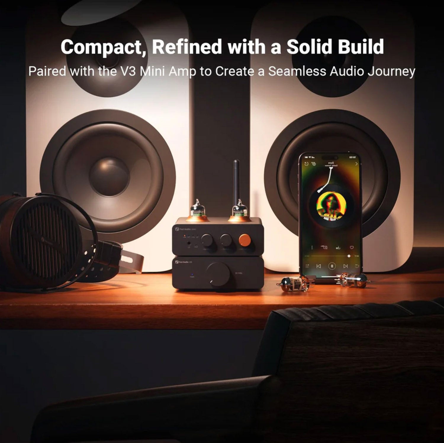Audio equipment including speakers and a mini amp on a wooden surface with a phone displaying music.