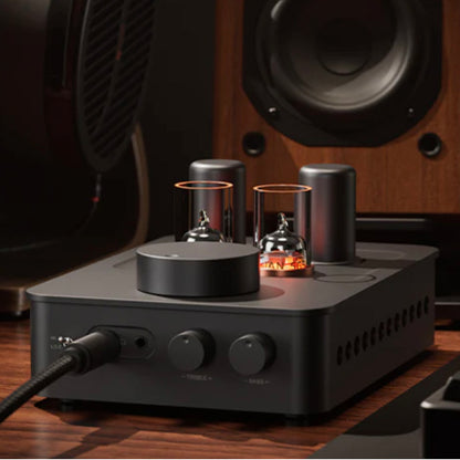 Fosi Audio GR70 Tube Headphone Amp Preamp with vacuum tubes on a wooden surface, with speakers in the background.