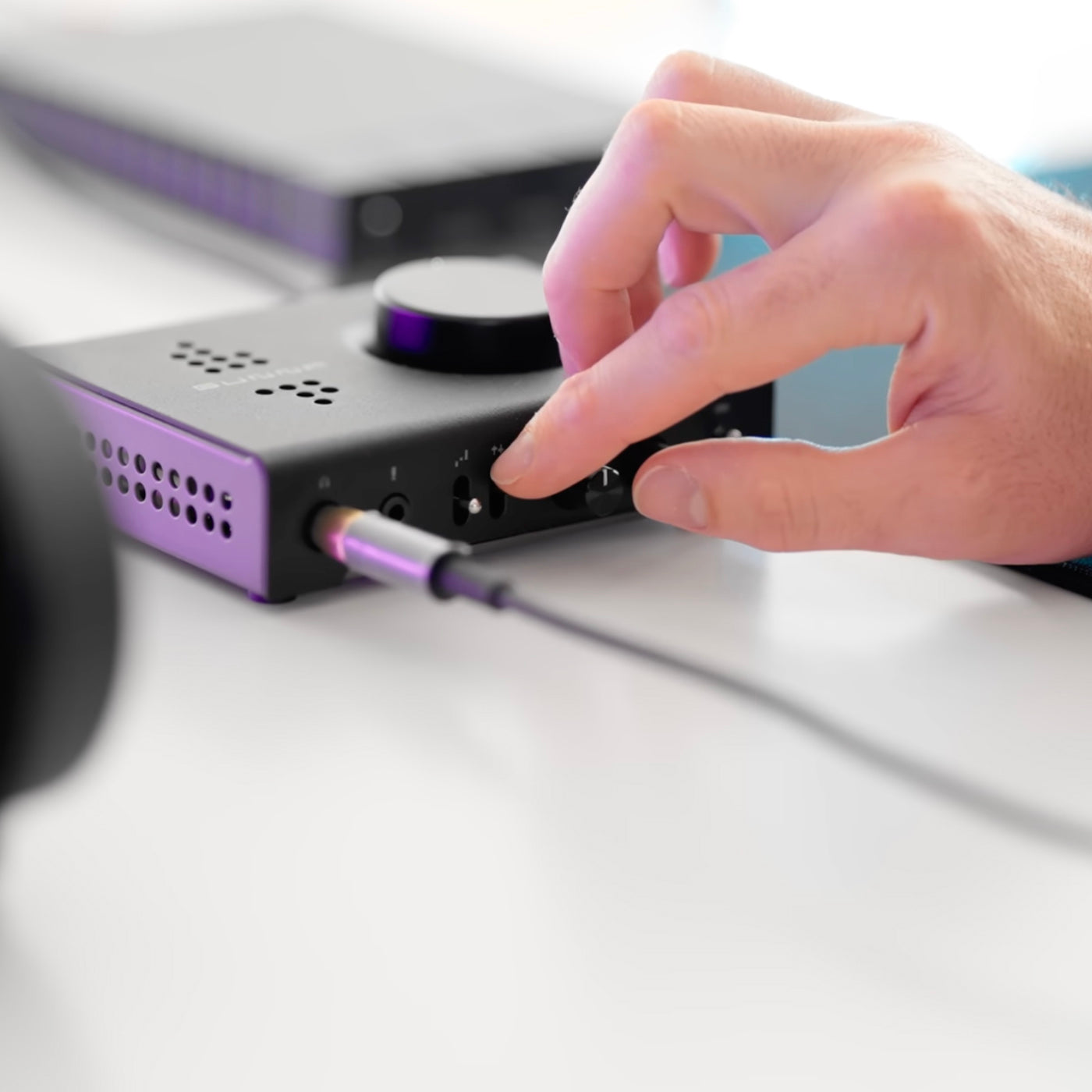Hand plugging a cable into a Fosi Audio K7 Desktop DAC Headphone Amplifier