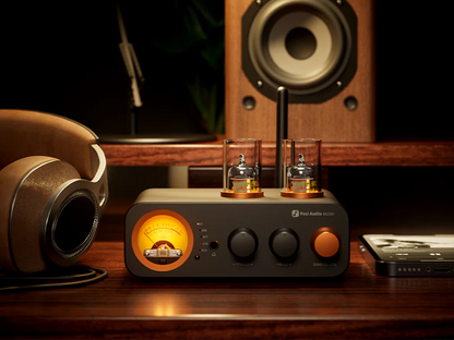 Audio equipment including a tube amplifier, headphones, and speakers on a wooden surface.