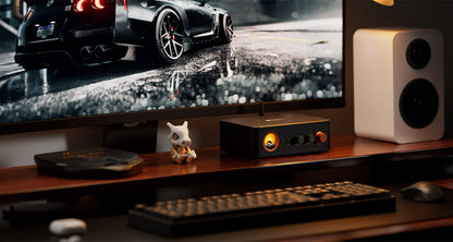 Gaming setup with TV, console, and speakers on a desk