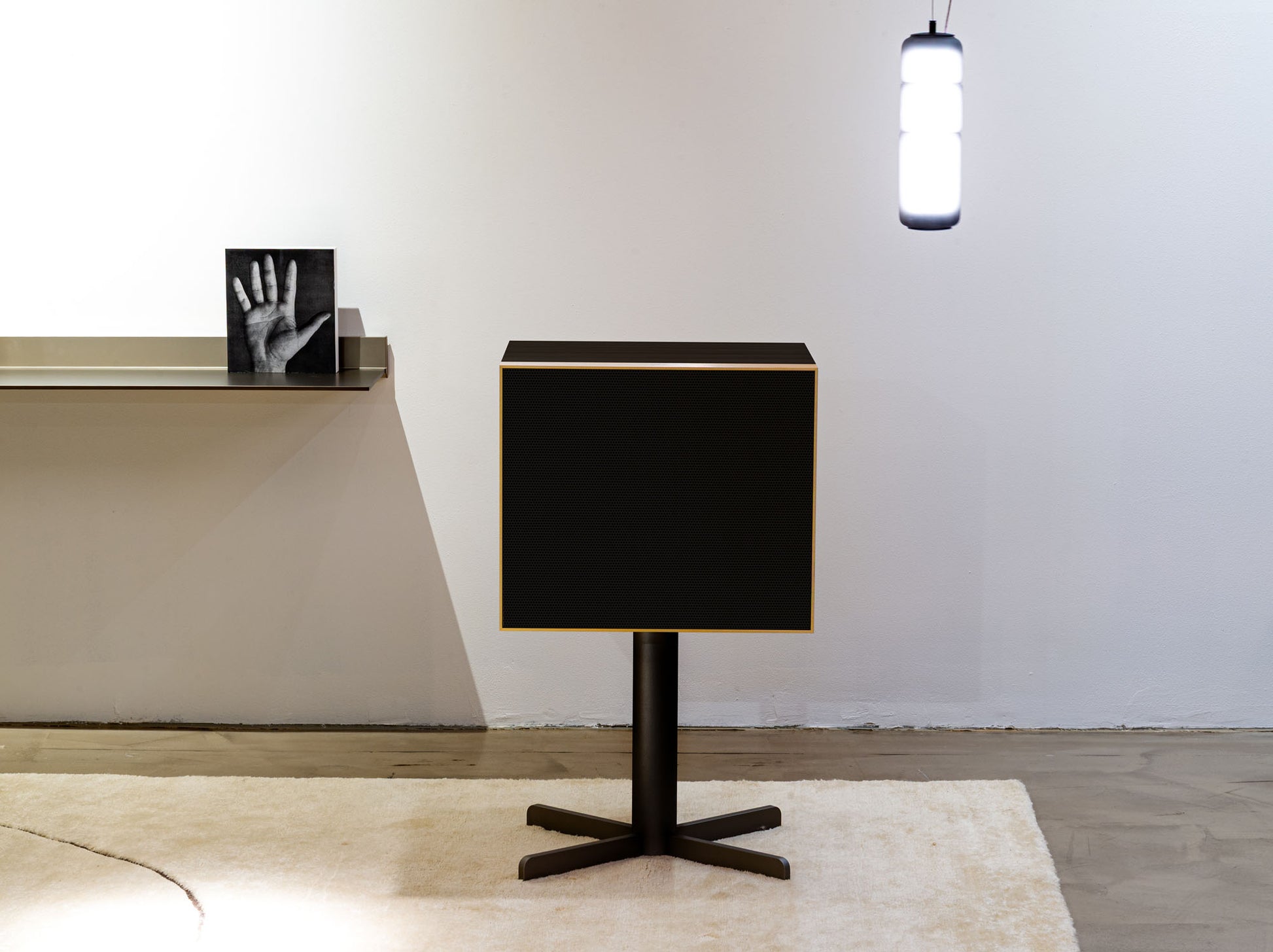 Modern black Geneva Speaker with a minimalist design in a room setting.