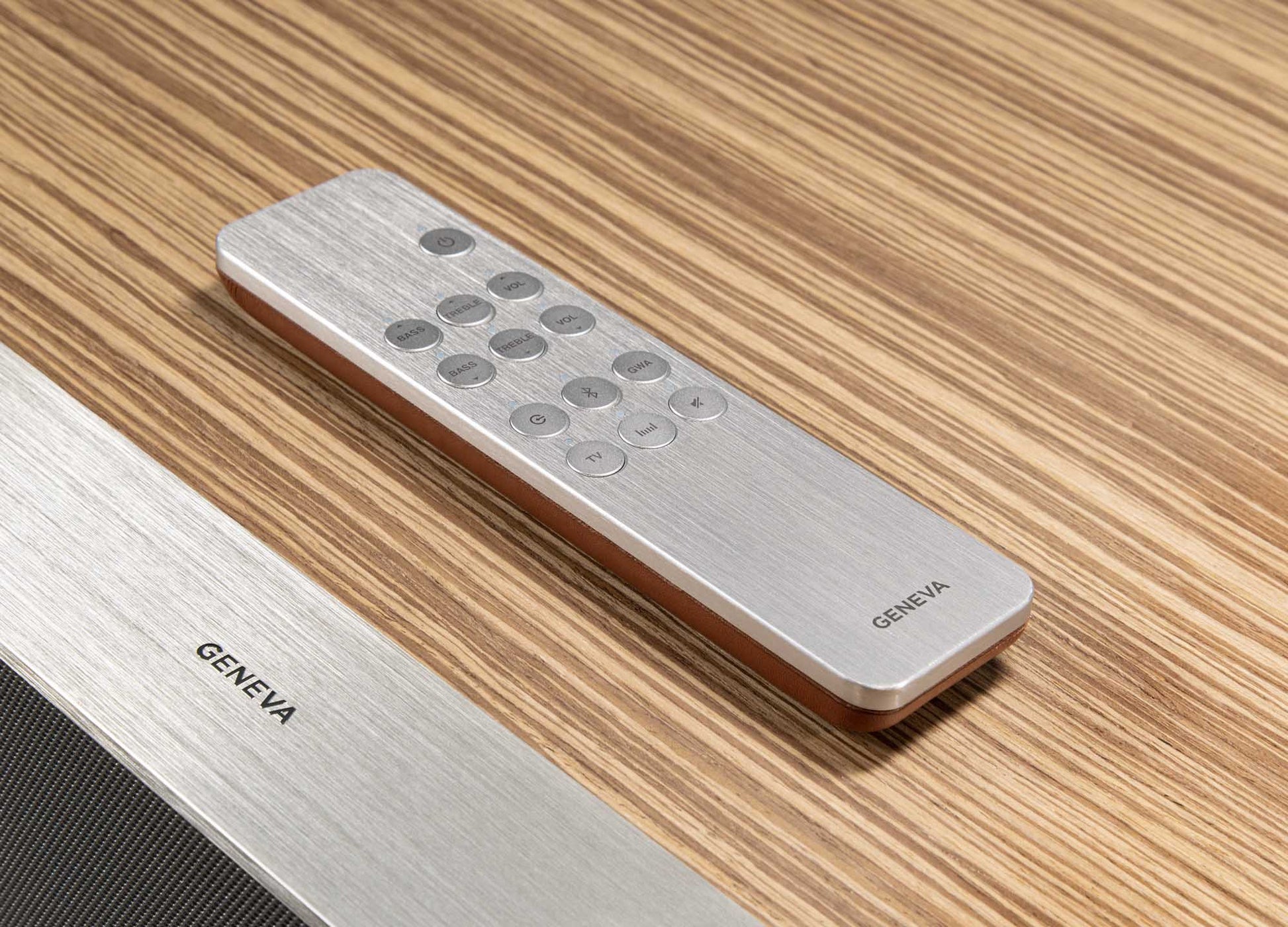 Silver remote control with 'GENEVA' branding on a Geneva Speaker