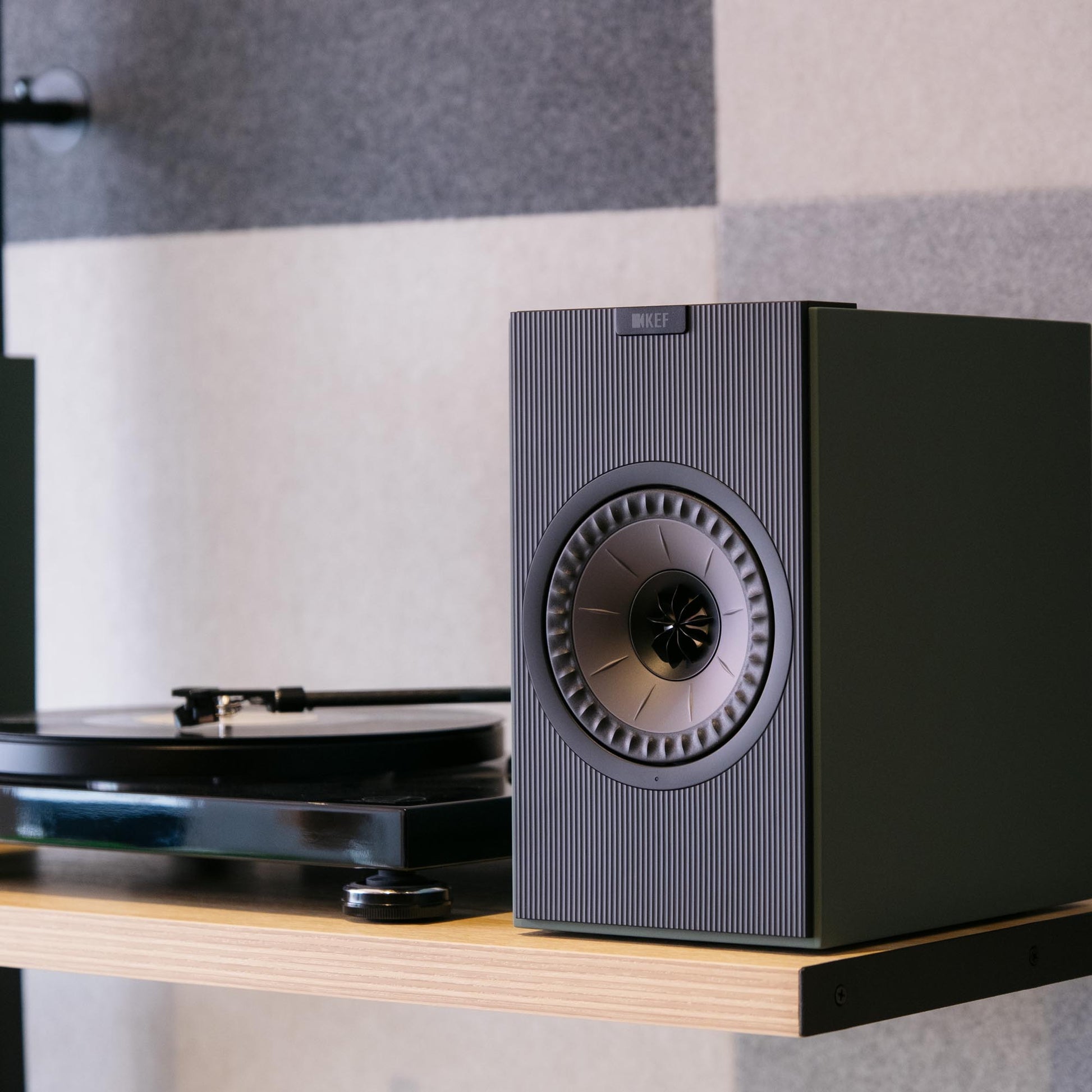 Green speaker on a shelf with a record player in the background