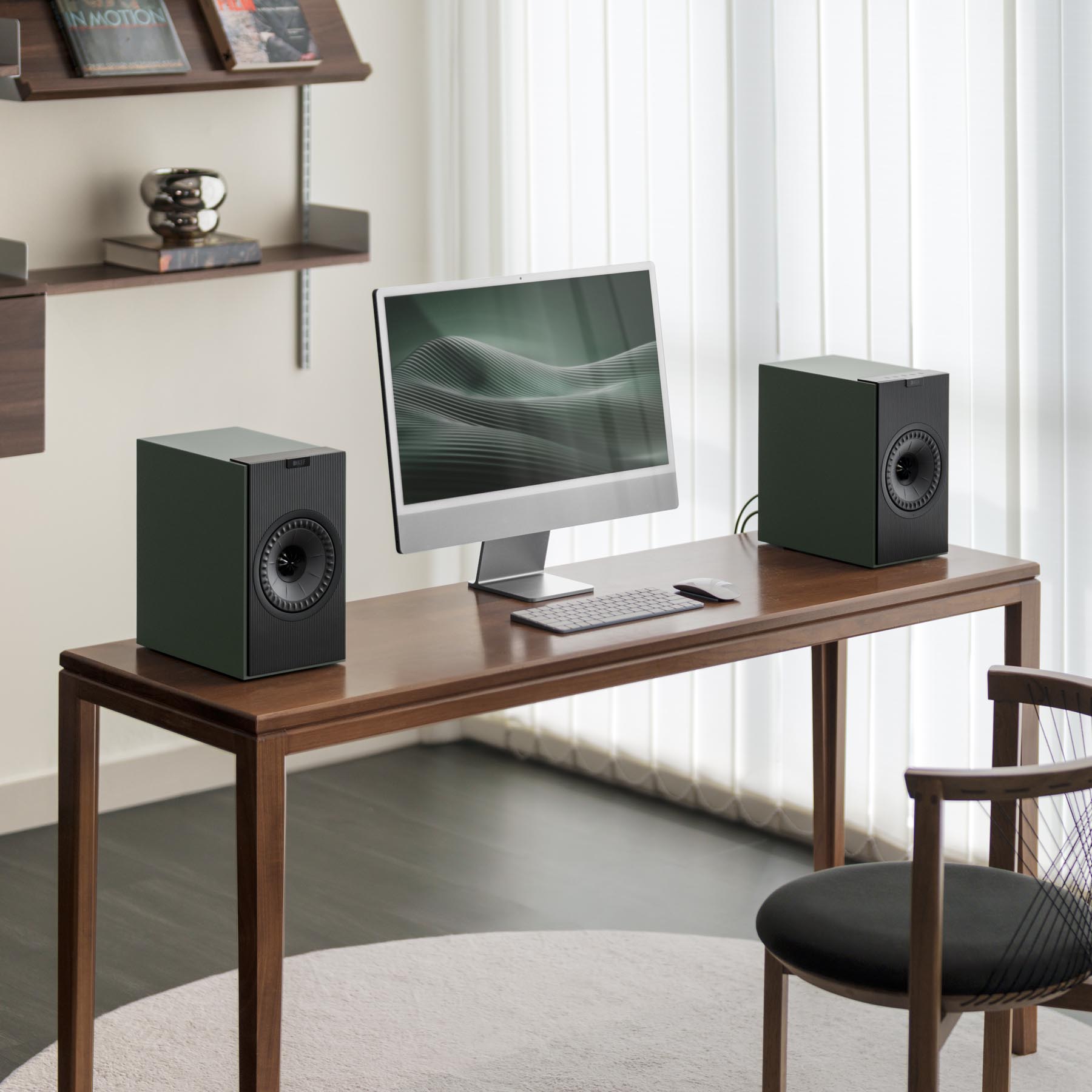 Modern home office setup with a desk, computer monitor, keyboard, and speakers.
