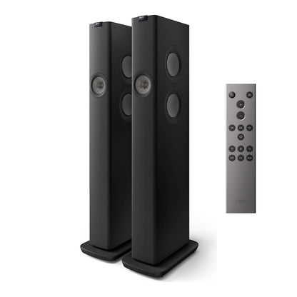 Pair of black floor-standing speakers with a remote control on a white background