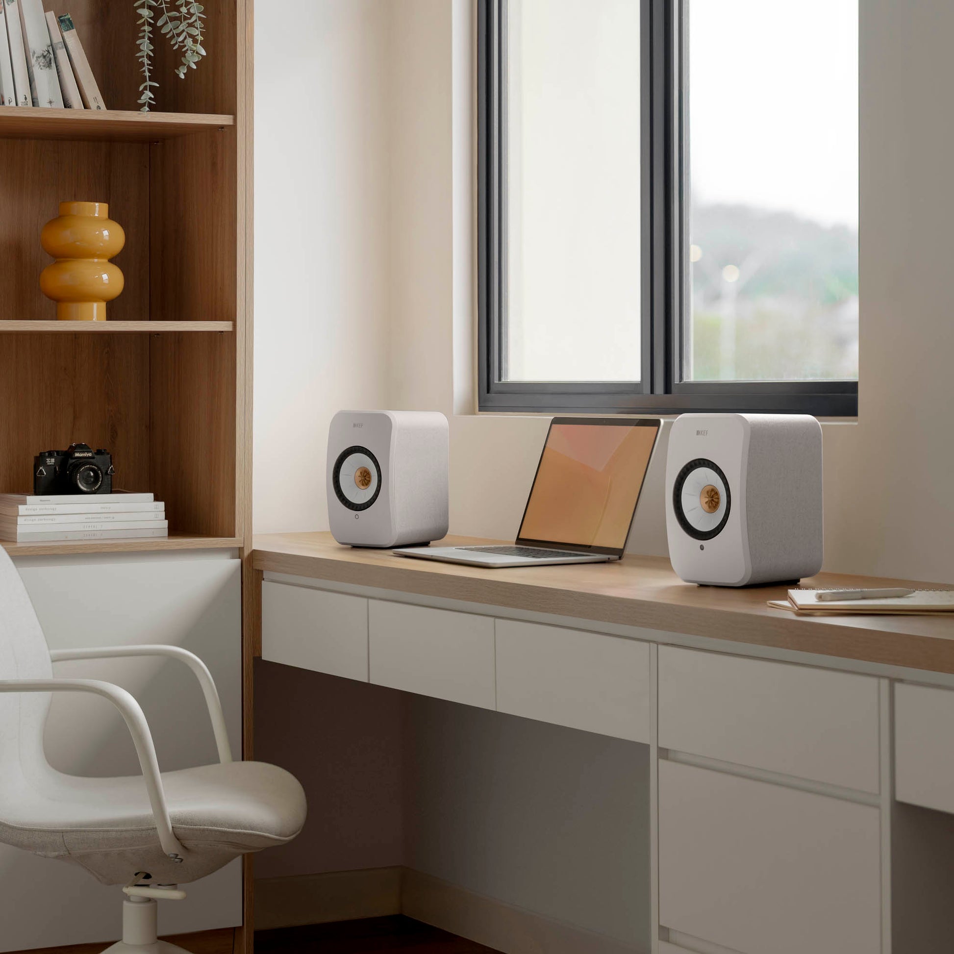 Modern home office with a desk, laptop, and speakers.