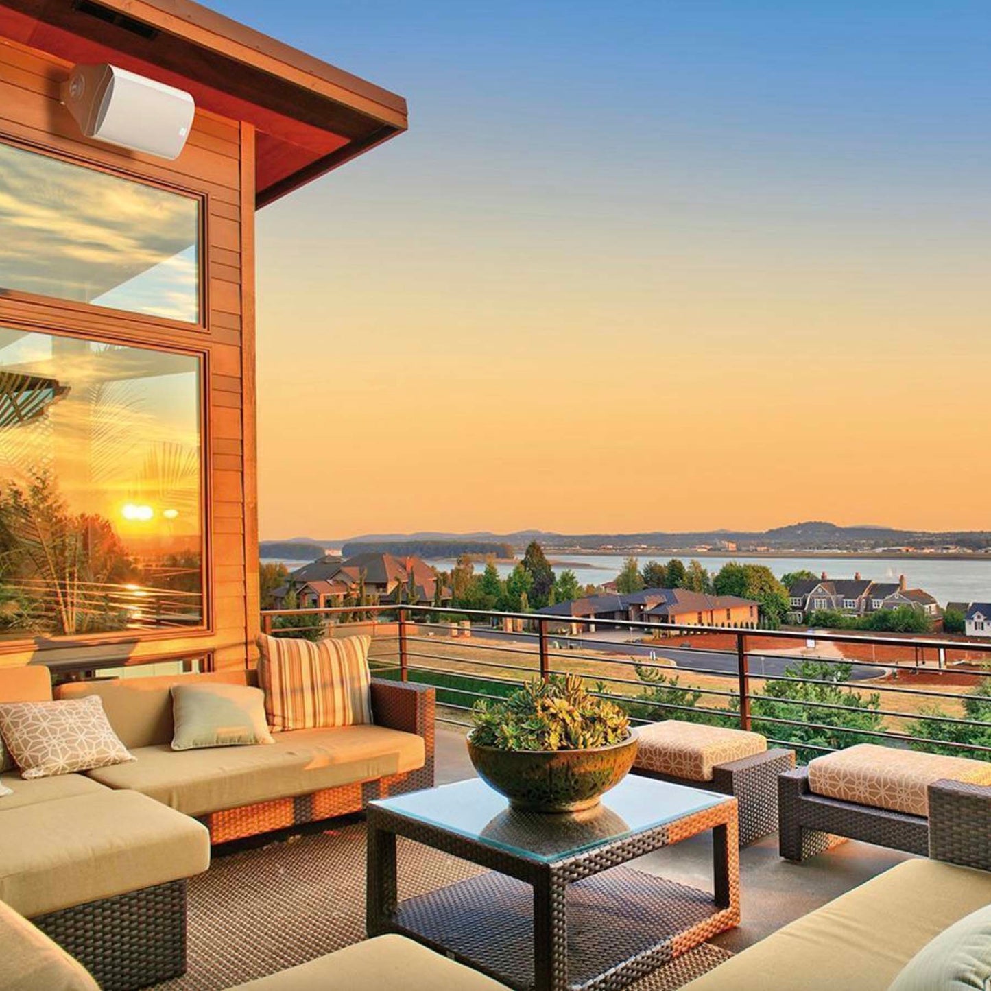 Outdoor patio with furniture and a scenic view of a lake at sunset.