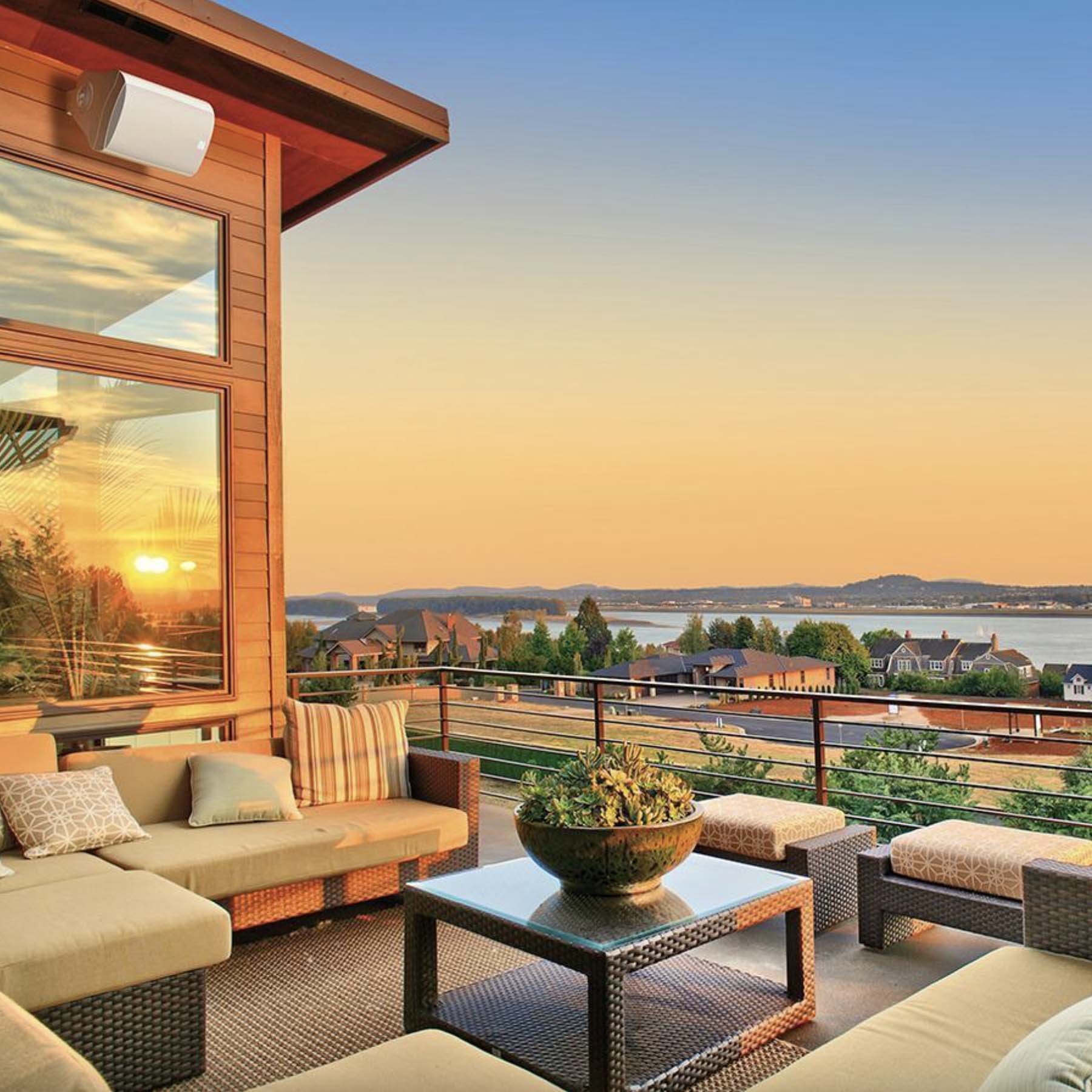 Outdoor patio with furniture and a scenic view of a lake at sunset.