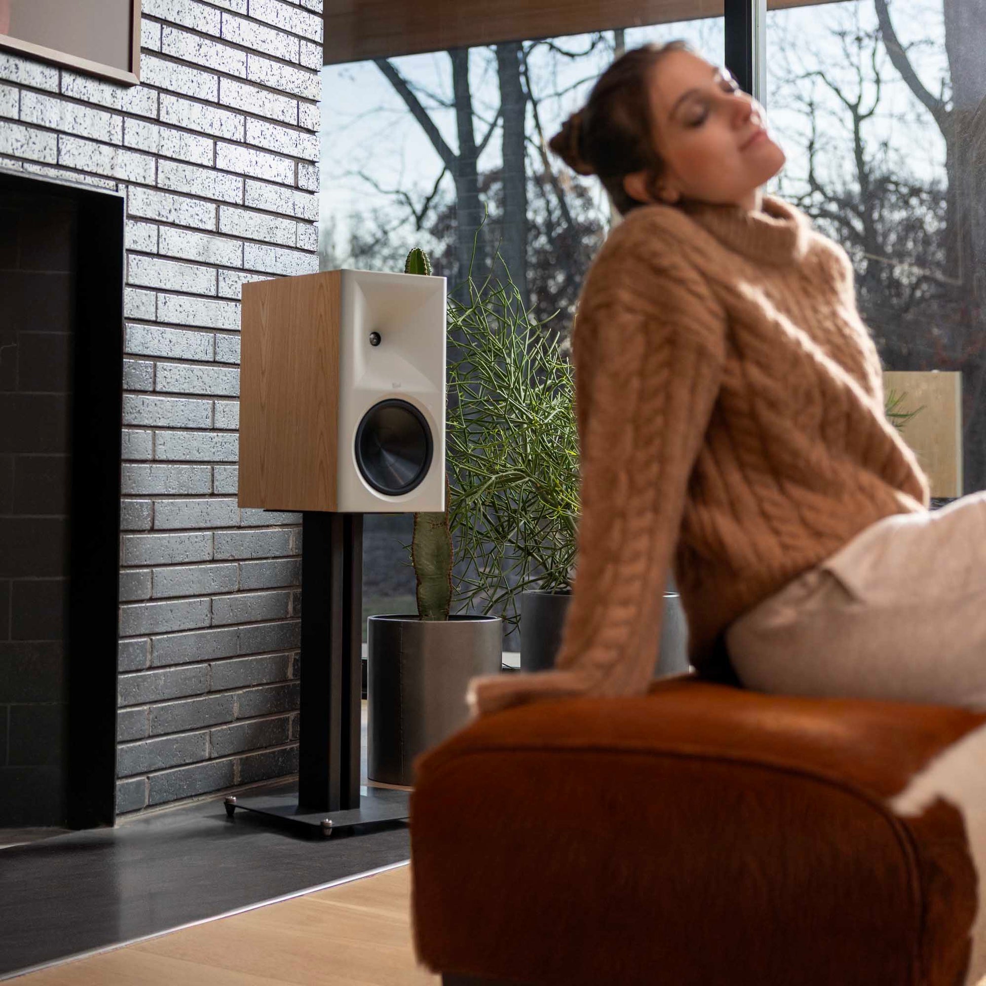 Woman relaxing on a couch in a modern living room with a speaker and plant.