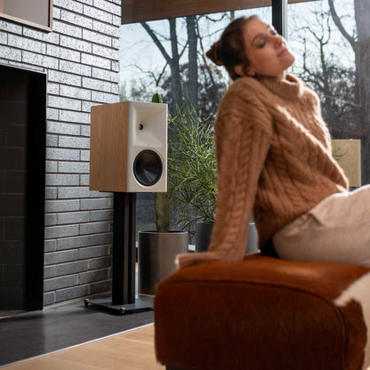 Woman relaxing on a couch in a modern living room with a speaker and plant.
