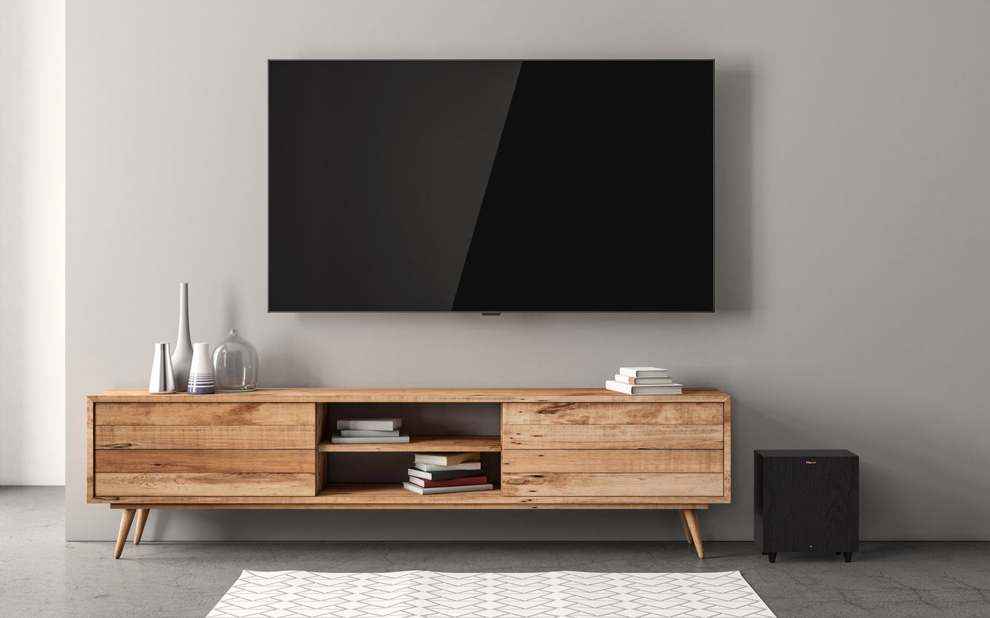 Wooden TV stand with a large flat-screen TV mounted on a gray wall.