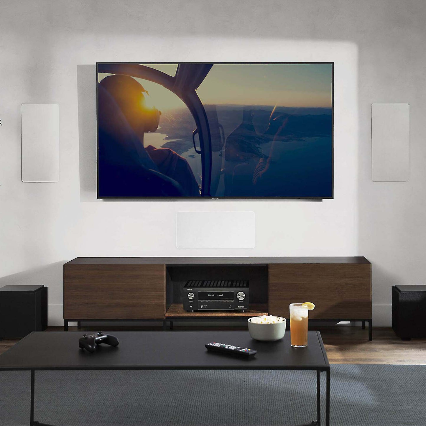 Modern living room with a large TV displaying an airplane scene, wooden entertainment console, and decorative items.