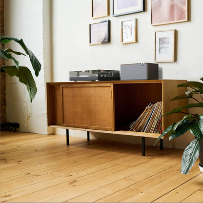 Klipsch The Three Plus Bluetooth Speaker on cabinet with turntable and timber floors