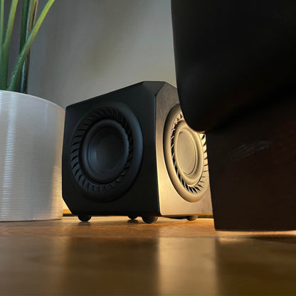 Lithe Audio Wireless Micro Subwoofer placed on the floor next to pot