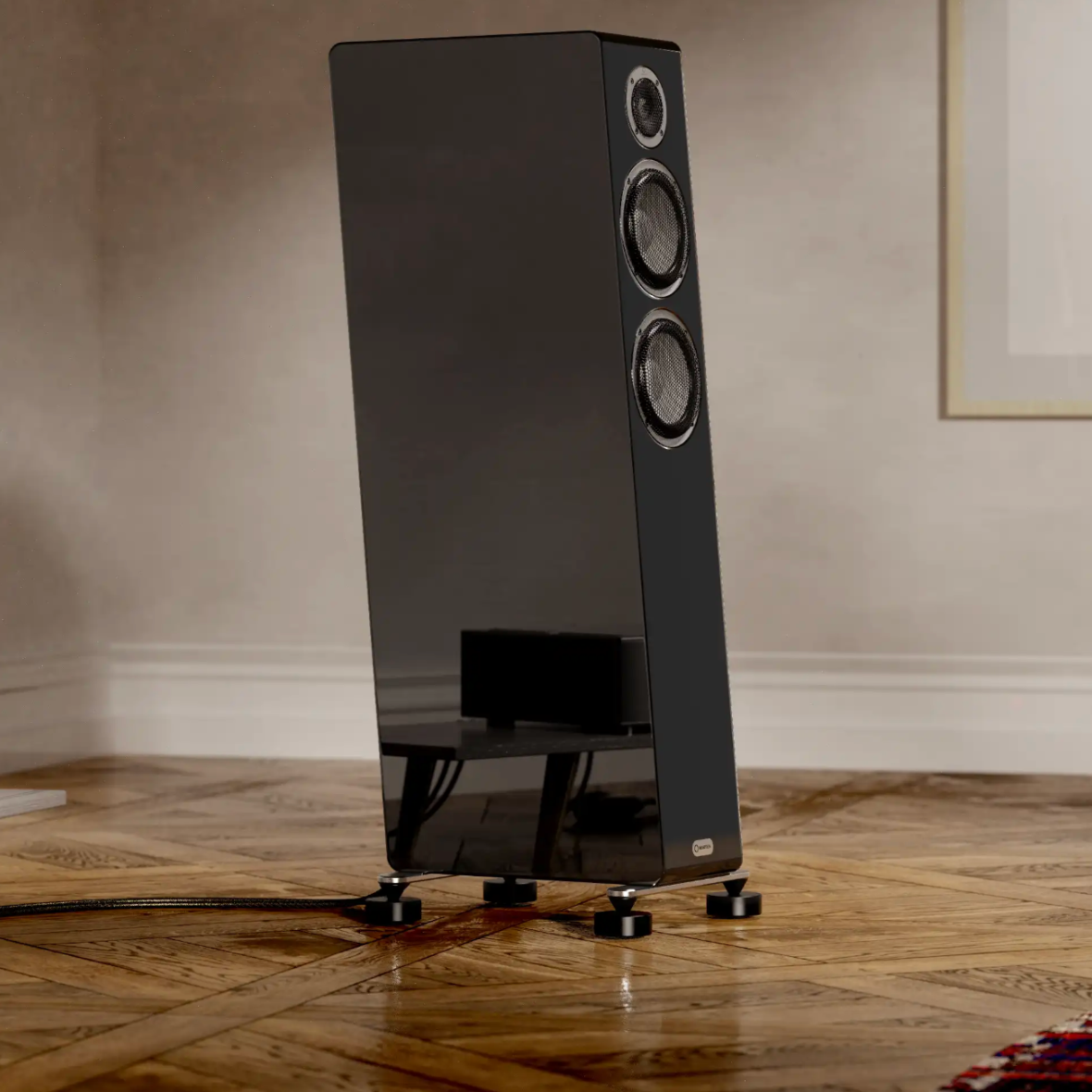 Black floor-standing speaker on a wooden floor with a neutral wall background