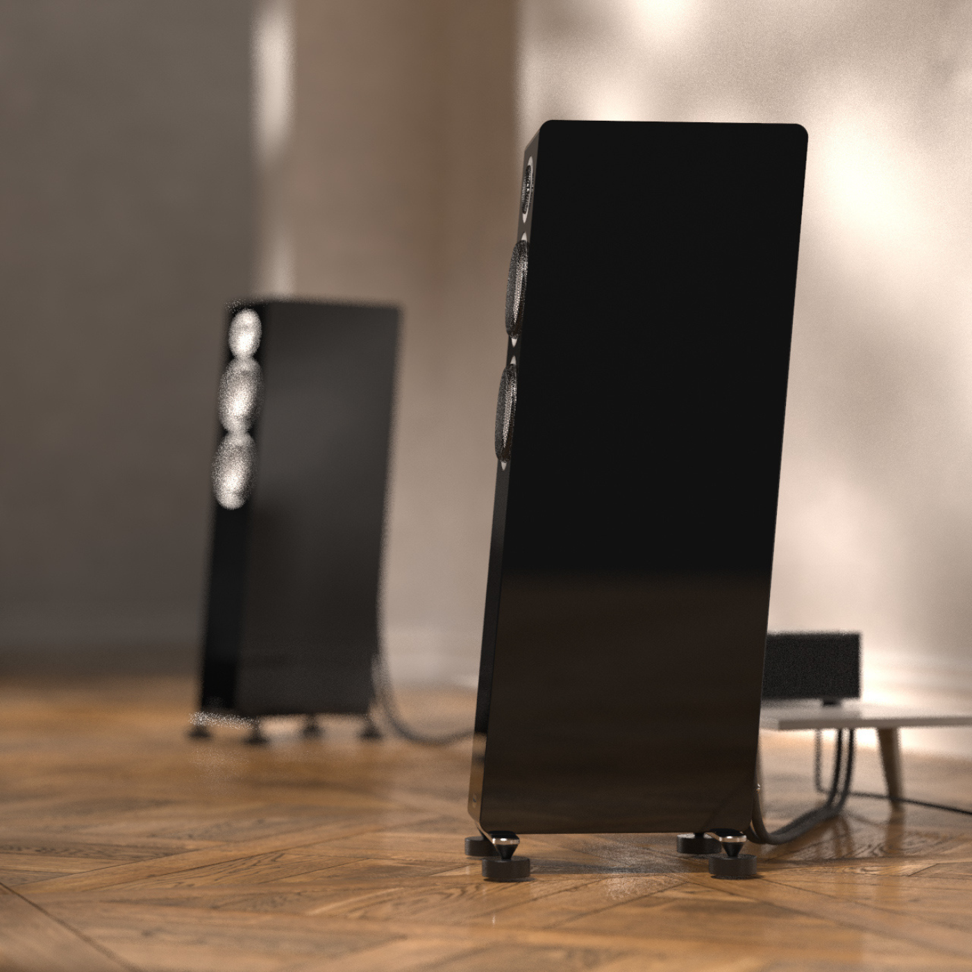 Black speakers on a wooden floor with a blurred background