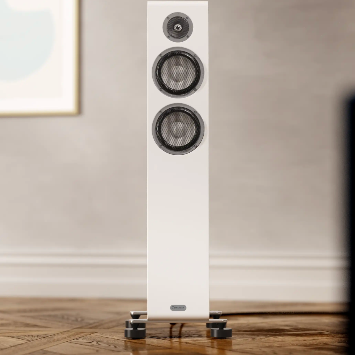Tall white floor-standing speaker on a wooden floor with a neutral wall background