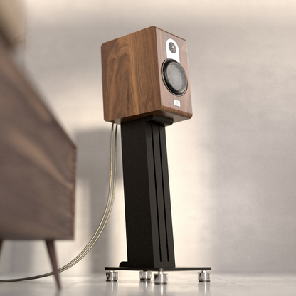Walnut Marten Parker Duo Bookshelf Speaker on a stand with a blurred chair in the background