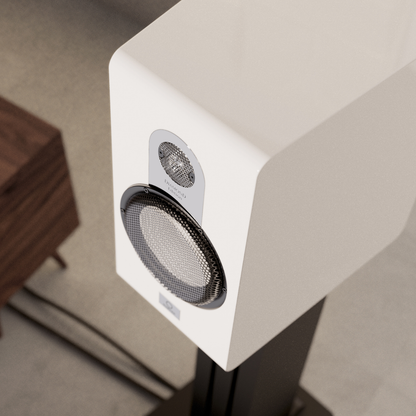 White speaker on a gray surface with a wooden object in the background