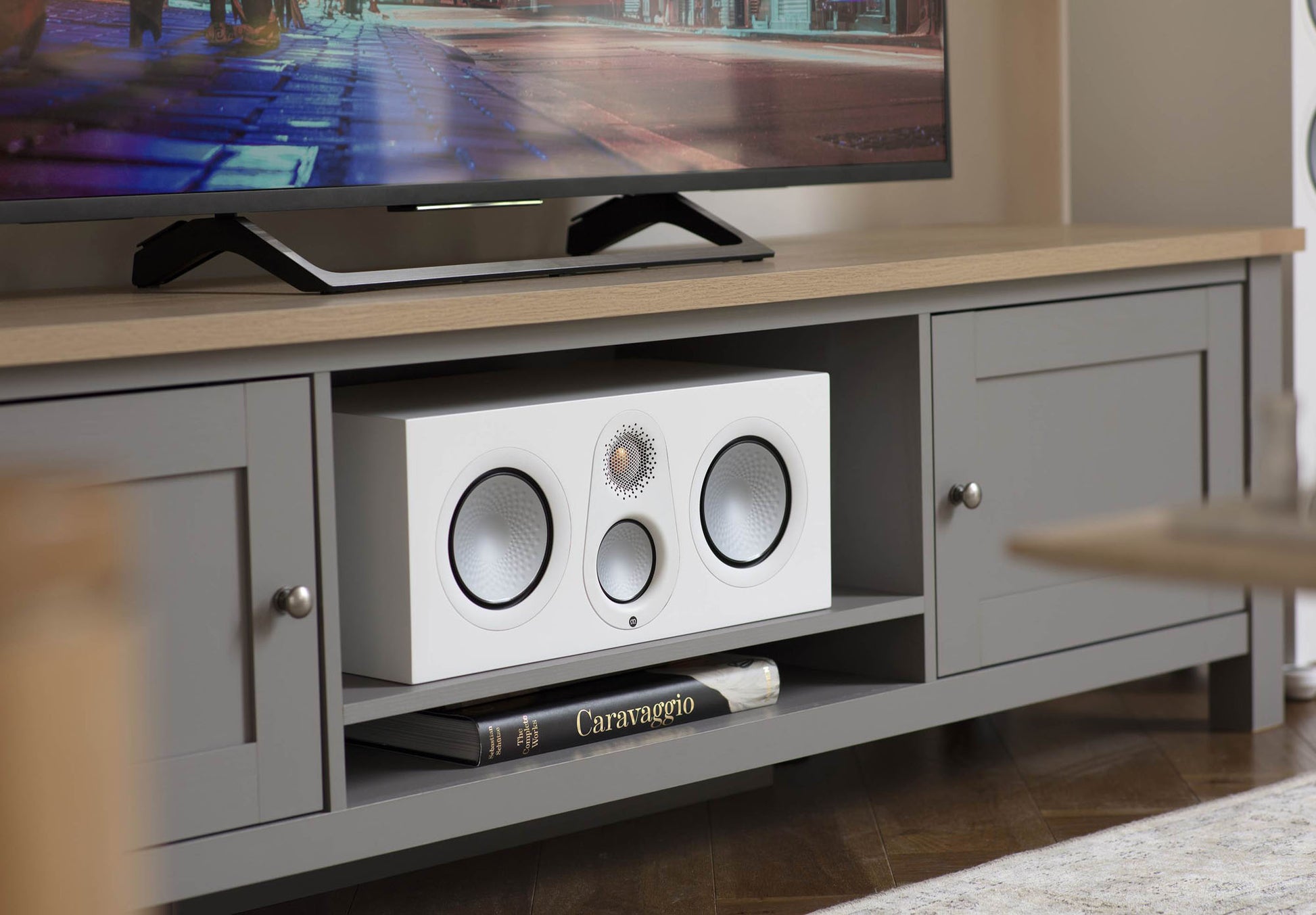 White audio equipment in a gray entertainment console with a TV above