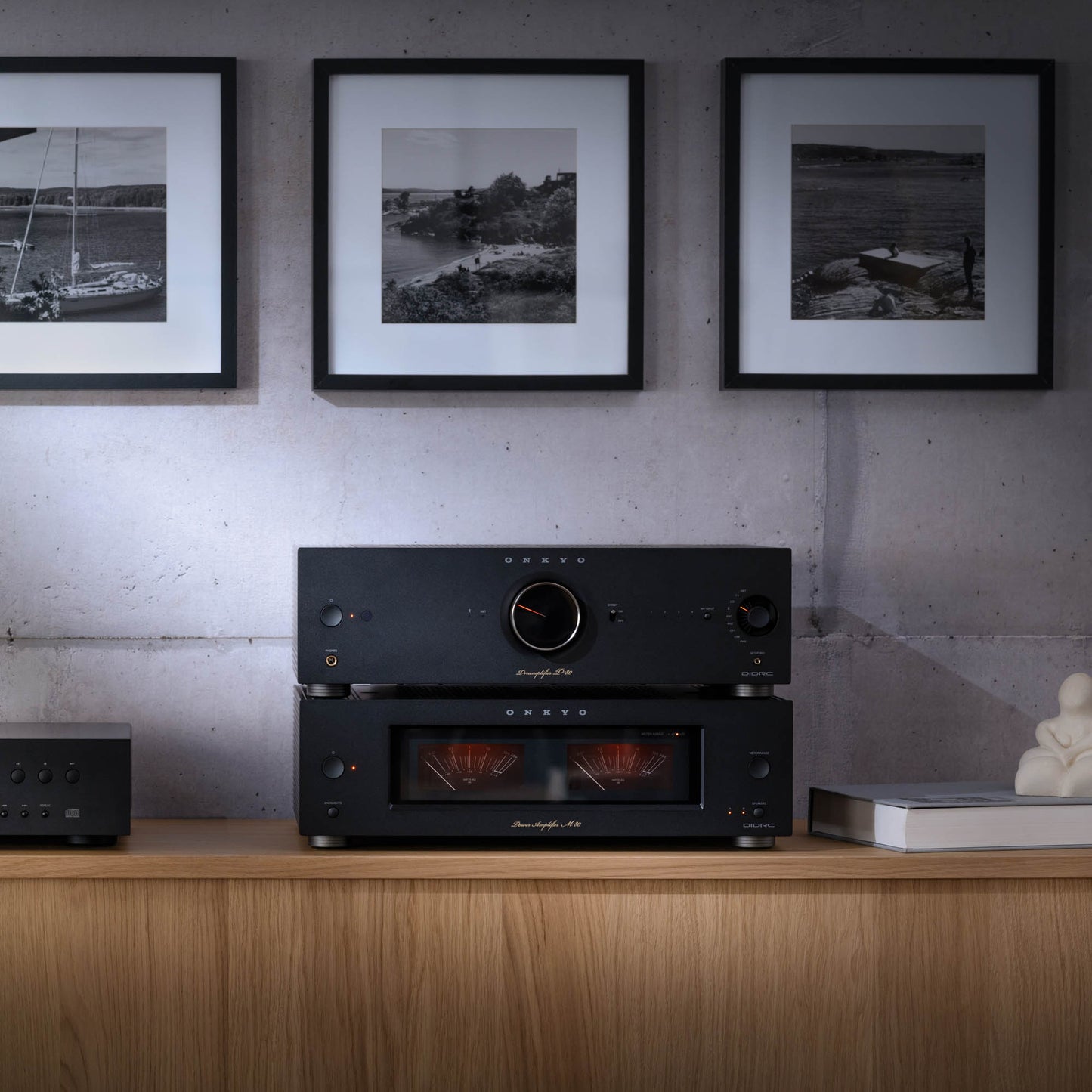 Black audio equipment on a wooden shelf with framed black and white photos on the wall.