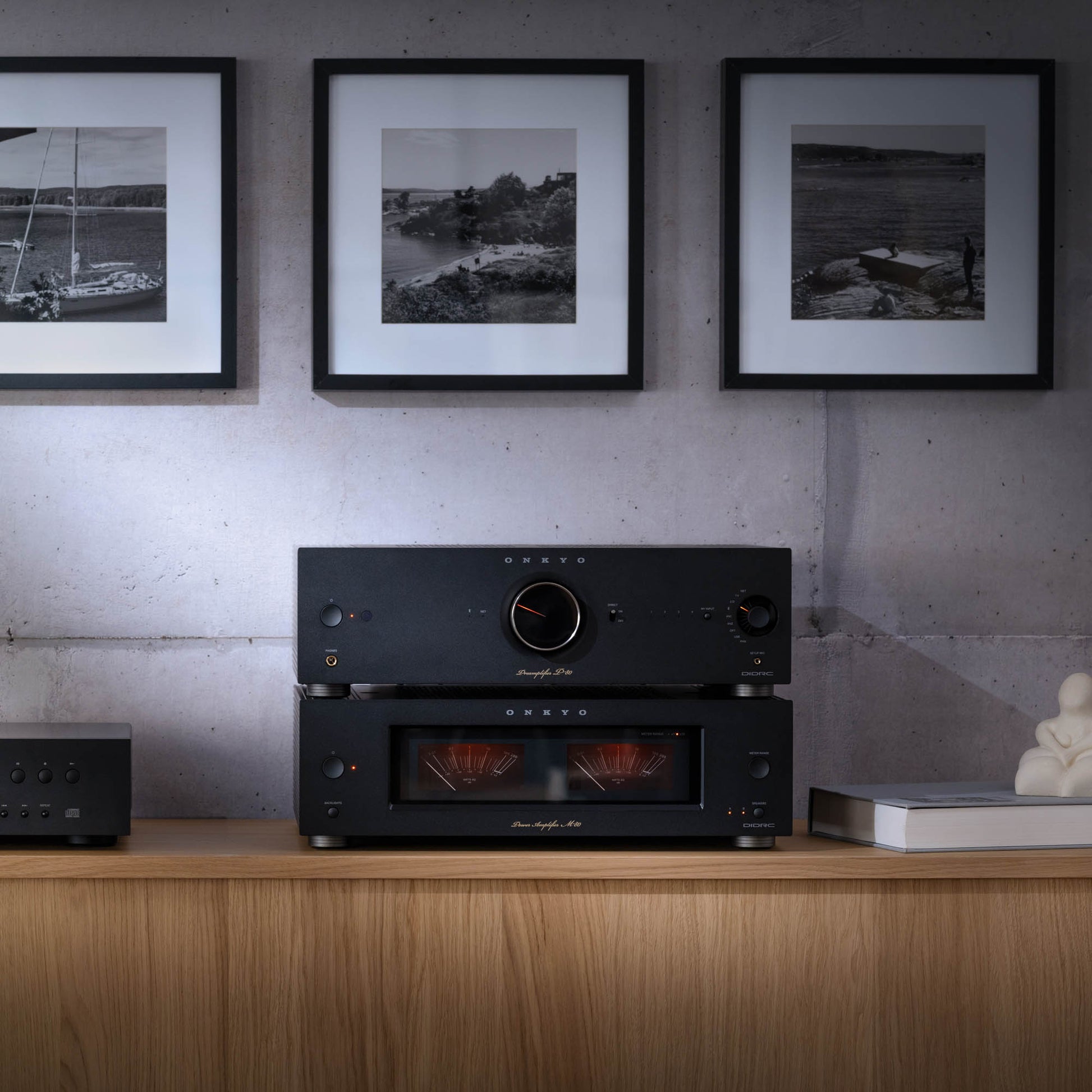 Black audio equipment on a wooden shelf with framed black and white photos on the wall.