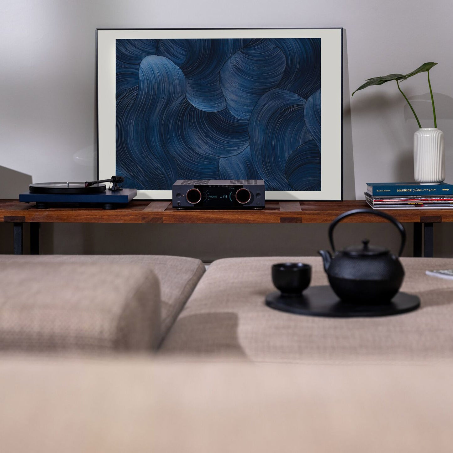 Living room setup with a framed abstract art piece, record player, and teapot.