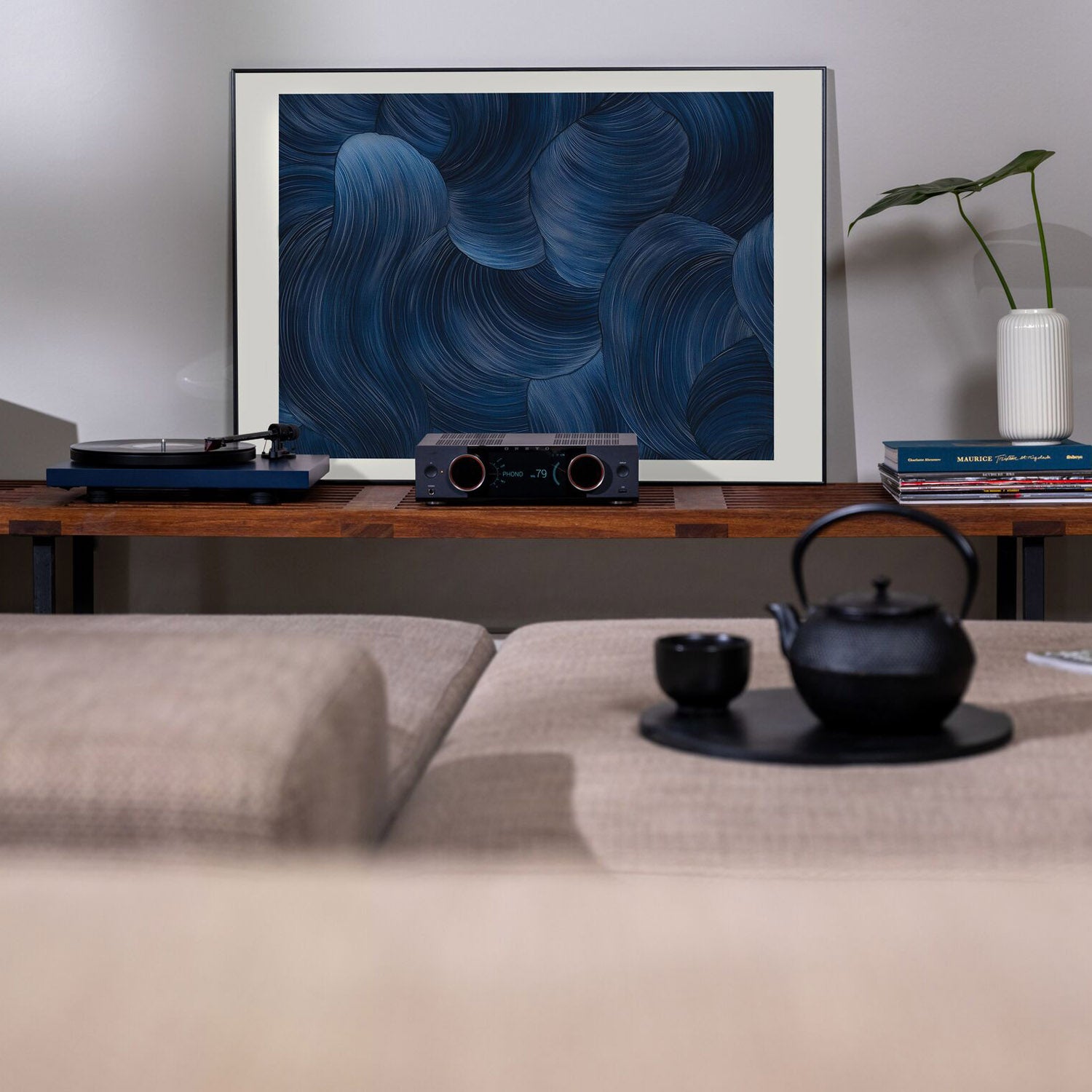 Living room setup with a framed abstract art piece, record player, and teapot.