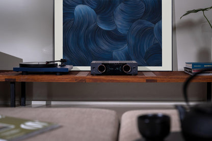 Audio equipment on a wooden shelf with a blue abstract painting in the background
