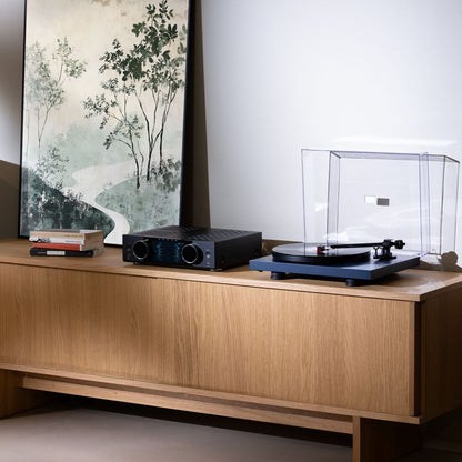 Turntable setup on a wooden console with a painting in the background
