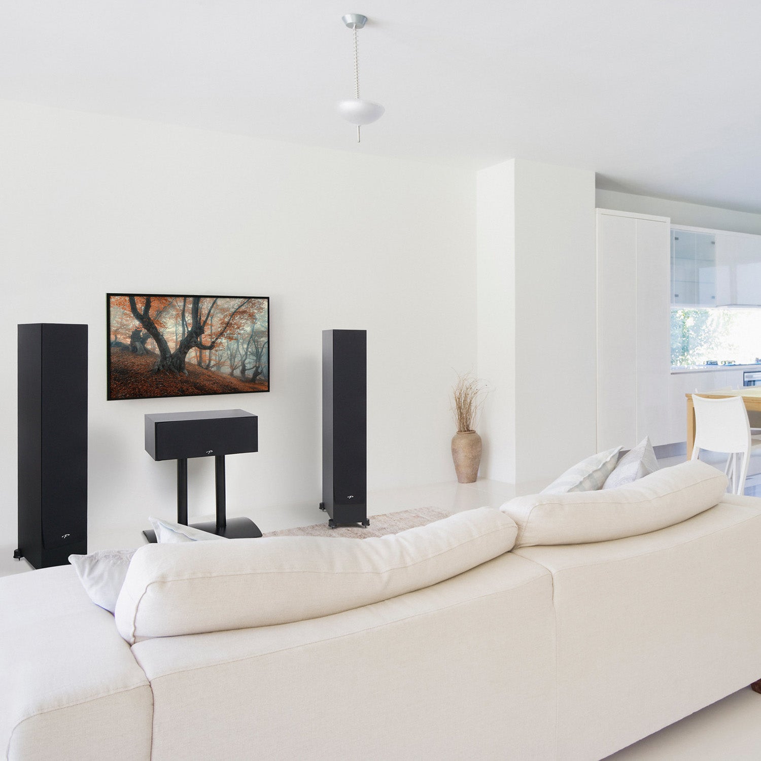 Modern living room with white walls, a beige sofa, and high-end speakers.