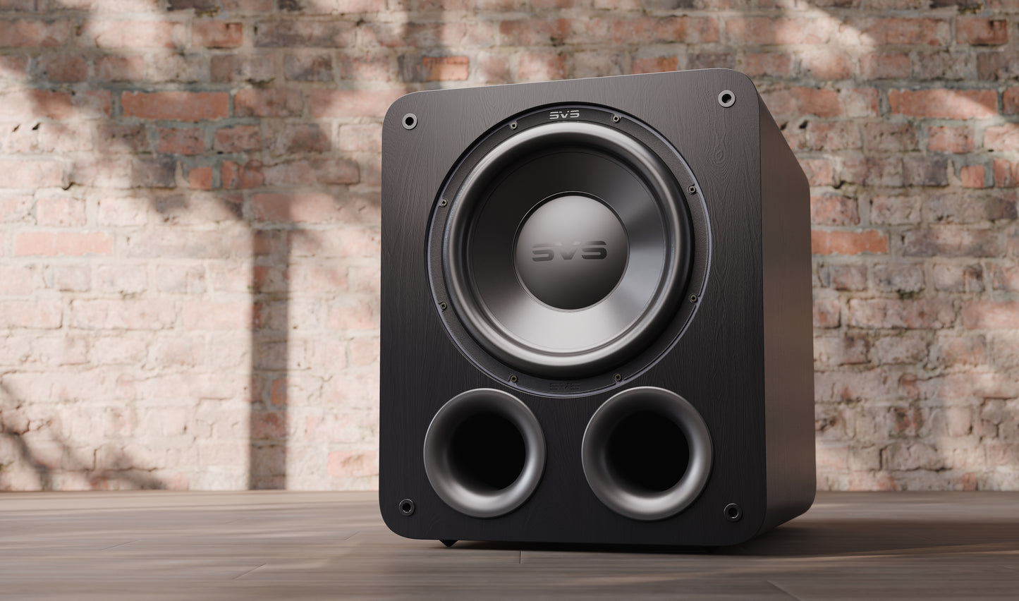 Black subwoofer on a wooden surface with a brick wall background