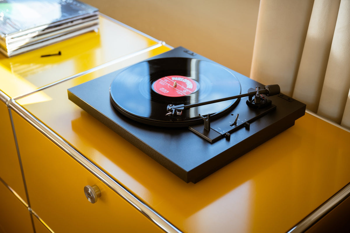 Record player on a yellow cabinet with a pink record