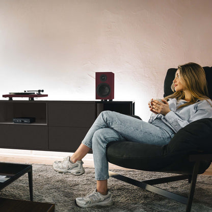 Woman sitting in a modern living room with a turntable and speakers.