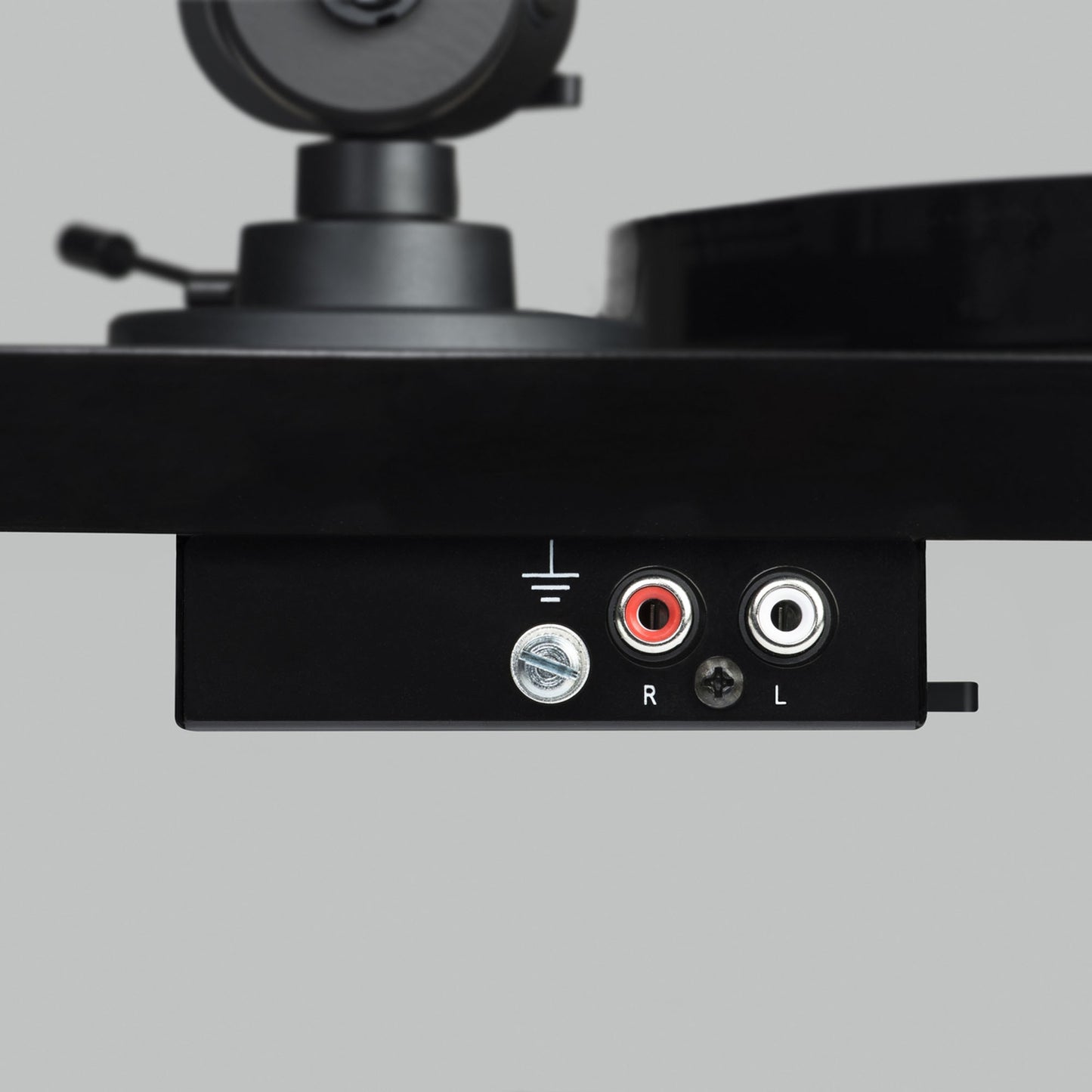 Close-up of a turntable with audio connection ports on a gray background