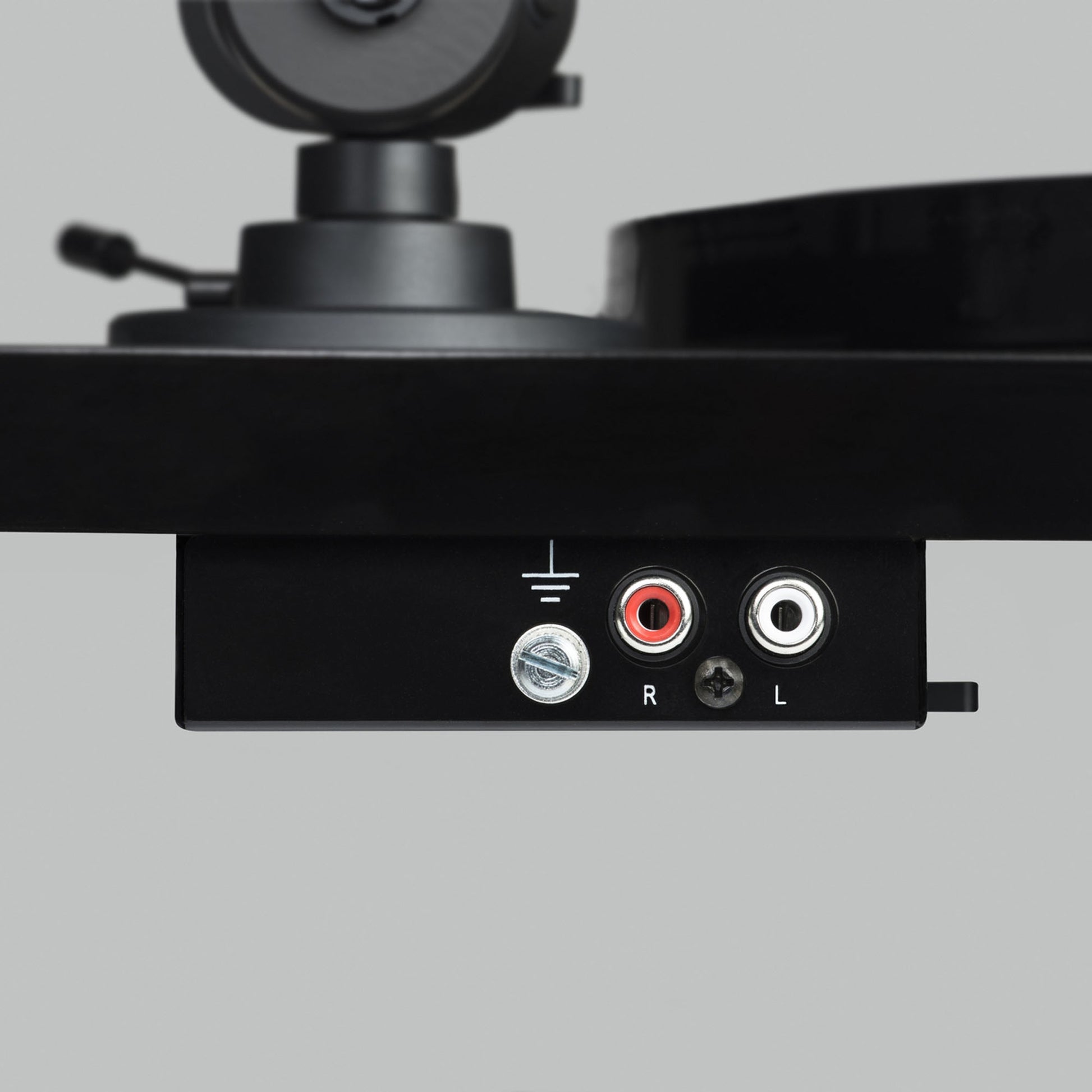 Close-up of a turntable with audio connection ports on a gray background