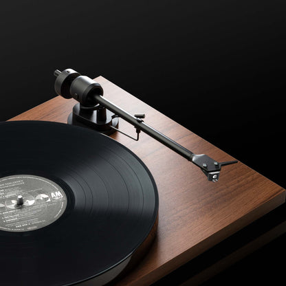 Turntable with a vinyl record on a wooden plinth against a black background