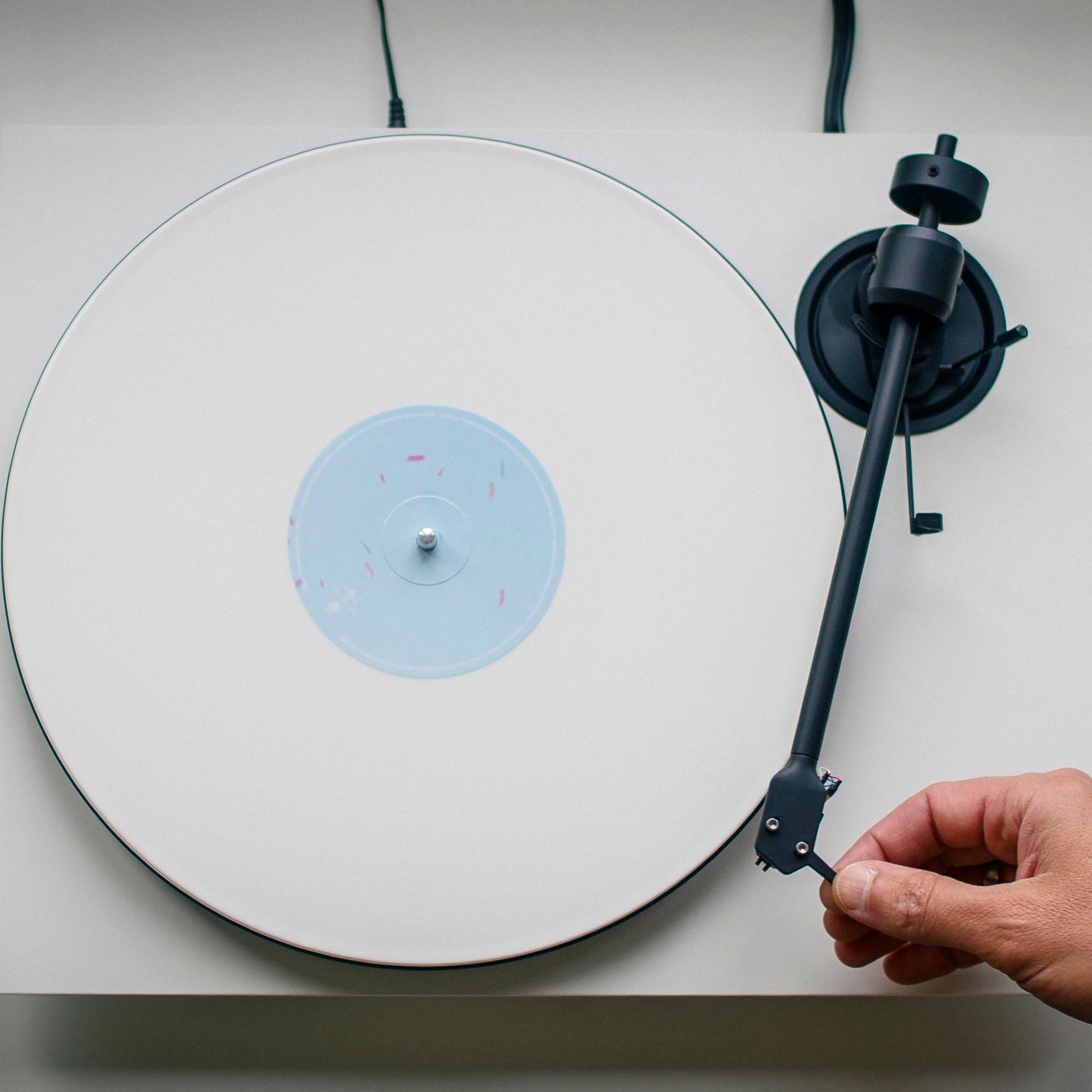 Person adjusting a turntable cartridge on a white turntable