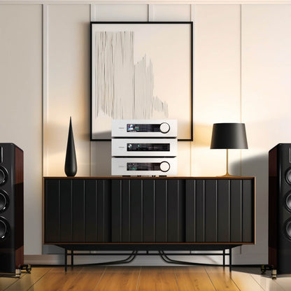 Modern audio equipment on a wooden console with a lamp and abstract art in a room.