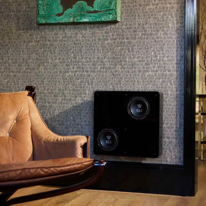 Black subwoofer mounted on a textured wall next to a brown armchair.