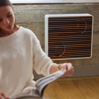 Woman reading a book with a white Subwoofer mounted on the wall behind her