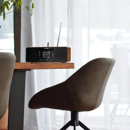 Modern radio on a wooden stand with a brown chair in a bright room.